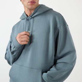 Model wearing 247 hoodie in dusky navy, oversized fit with drawstring hood and kangaroo pocket, relaxed cotton style