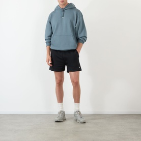 Model wearing 247 hoodie in Dusky Navy with black shorts and grey trainers with white socks.