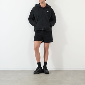Model wearing 247 Jet Black cotton shorts, styled with matching black zip-up hoodie and black trainers.