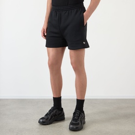 Model wearing 247 jet black cotton shorts with elasticated waist, styled with black socks and chunky trainers