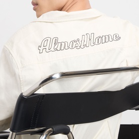 Model wearing Almost Home Logo Bowling Shirt in Cloudskin, back view showing embroidered script logo across upper back in cotton fabric