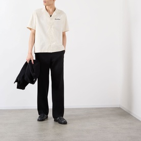 Model wearing Almost Home Logo Bowling Shirt in Cloudskin with black straight-leg trousers and black loafers, holding a black jacket.