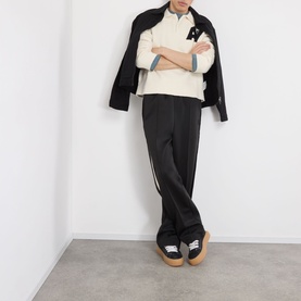 Model wearing Almost Home Cloudskin cotton polo, styled with black trousers, dark jacket and chunky sole trainers.