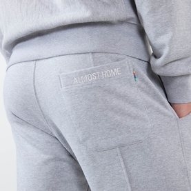 Model wearing Almost Home Workwear Logo Sweatpants in Gym Grey, close-up of rear patch pocket with embroidered logo detail.