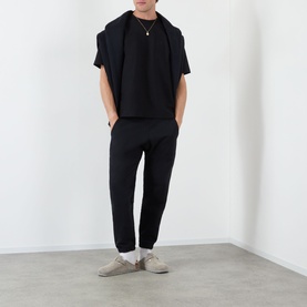 Model wearing Almost Home Workwear Logo Sweatpants in Porto Black, tapered leg with cuffed ankles, styled with black tee and beige trainers