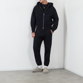 Model wearing Almost Home Workwear Logo Sweatpants in Porto Black, tapered leg with cuffed ankles, styled with matching black zip hoodie and white