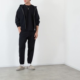 Model wearing Almost Home Workwear Logo Zip Hoodie in Porto Black with matching black joggers and beige trainers.