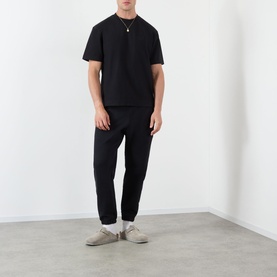 Model wearing Almost Home Workwear Logo T-Shirt in Porto Black with matching black joggers and grey suede trainers.