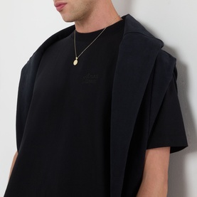 Model wearing Almost Home Workwear Logo T-Shirt in Porto Black with crew neck and tonal chest logo, styled with a black blazer and gold pendant