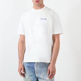 Model wearing Almost Home Blue Print T-Shirt in white with small chest logo graphic, styled with light wash jeans.
