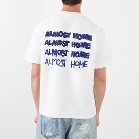 Model wearing Almost Home T-Shirt in white with blue repeated logo print to back, styled with light wash denim jeans