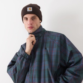 Model with Carhartt Watch Logo Beanie Hat in Tobacco, ribbed knit with turned-up brim and logo patch, styled with green tartan jacket