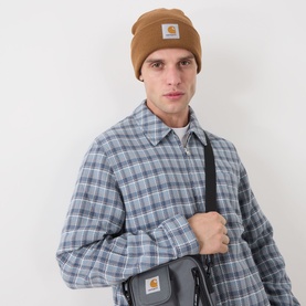 Model with Carhartt Watch Logo Beanie Hat in Hamilton Brown, ribbed knit with turned-up brim, styled with plaid shirt and crossbody bag