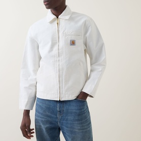 Model wearing Carhartt Detroit Casual Jacket in Wax, white heavyweight canvas, gold zip, logo badge, chest pocket, styled with blue jeans
