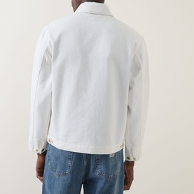 Model wearing Carhartt Detroit Casual Jacket in Wax, back view, styled with blue jeans. Heavyweight canvas, tonal collar, snap button hem.