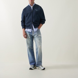 Model wearing Carhartt Carbon/White cotton casual jacket with light blue shirt, distressed wide-leg jeans and grey trainers.
