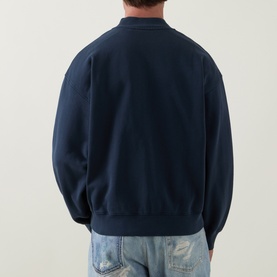Model wearing Carhartt casual jacket in Carbon, rear view, styled with distressed light-wash jeans