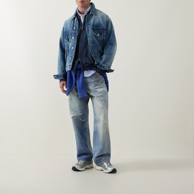 Model wearing Carhartt casual jacket in Carbon/White denim, styled with distressed blue jeans, layered shirts, and grey trainers.