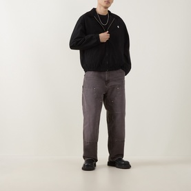 Model wearing Carhartt Madison Ripstop Padded Jacket in Black/Wax, styled with grey cargo trousers and black chunky shoes.