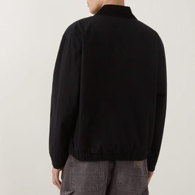 Model wearing Carhartt Madison Ripstop Padded Jacket in Black/Wax, rear view showing elasticated hem, ribbed cuffs and collar, styled with grey