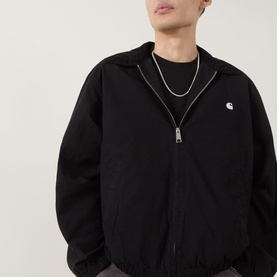 Model wearing Carhartt Madison Ripstop Padded Jacket in Black/Wax with zip fastening and embroidered logo, styled with black crew-neck tee and silver
