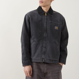 Model wearing Carhartt OG Detroit Jacket in Black, showing corduroy collar, zip fastening, chest pocket and woven logo badge