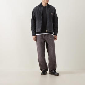 Model wearing Carhartt OG Detroit Jacket in Black, styled with grey distressed jeans and black leather shoes.