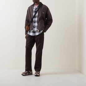 Model wearing Carhartt OG Detroit Logo Jacket in Tobacco, styled with check shirt, dark trousers and chunky trainers.