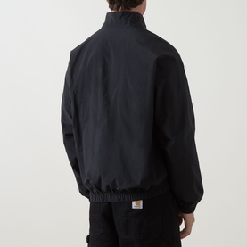 Model wearing Carhartt Travon Logo Windbreaker in Black, rear view showing stand collar, elasticated hem, and woven logo patch.