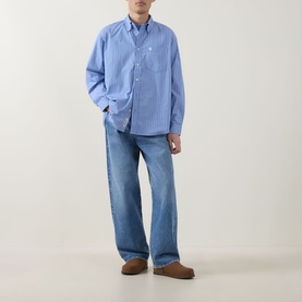 Model wearing Carhartt Keene Stripe Shirt in Curacao blue stripe, with light wash wide-leg jeans and tan suede mules.