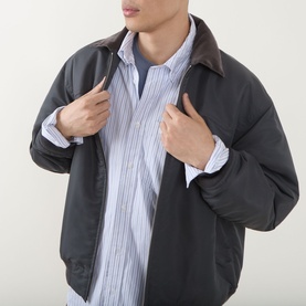 Model wearing Carhartt Casual Shirt in Keene Stripe/White, styled under a dark zip-up jacket with brown collar.