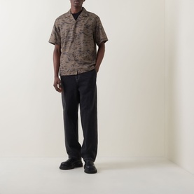 Model wearing Carhartt Travon Duck Feather Print shirt in Cypress/Black, styled with navy trousers and black loafers.