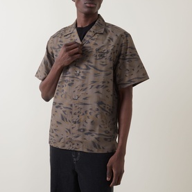 Model wearing Carhartt Travon Duck Feather Print shirt in Cypress/Black, short-sleeved bowling collar design with all-over duck feather print, styled