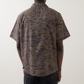Model wearing Carhartt Travon Duck Feather Print shirt in Cypress/Black, short sleeves, back view, paired with dark trousers