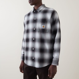 Model wearing Carhartt Tyers Logo Check Print Shirt in 3TQXX Check/Black, long sleeve with chest patch pocket, styled with dark trousers