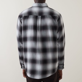 Model wearing Carhartt Tyers Logo Check Print Shirt in Check/Black, rear view showing pleat detail and curved hem.