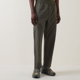 Model wearing Carhartt Flint Casual Trousers in Leaf, tapered leg with elasticated waistband, styled with grey trail trainers