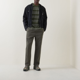 Model wearing Carhartt Flint Casual Trousers in Leaf, tapered leg, styled with striped tee and navy jacket.