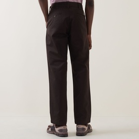 Model wearing Carhartt Master Casual Trousers in Tobacco, tapered-leg cut, rear jetted pockets visible, styled with brown loafers.