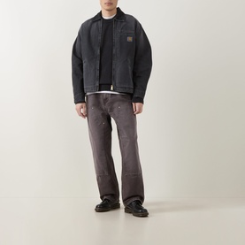 Model wearing Carhartt OG Double Knee Straight Jeans in Tobacco, styled with a black jacket, T-shirt, and black leather shoes.