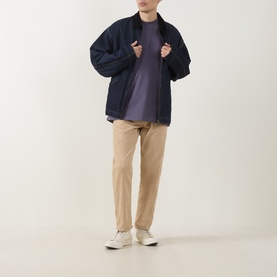 Model wearing Carhartt American Script Logo T-Shirt in Shady Purple, styled with navy zip jacket, beige trousers and white trainers.