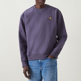 Model wearing Carhartt American Script Logo Sweatshirt in Shady Purple, crew neck with embroidered chest logo, styled with light blue jeans.