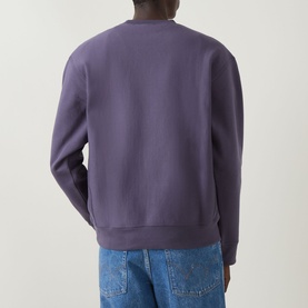 Model wearing Carhartt American Script Logo Sweatshirt in Shady Purple, crew neck, back view, styled with blue jeans.
