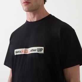 Model wearing Carhartt Bumper Stickers Logo T-Shirt in black, with graphic print slogan detail on chest in crew neck style.