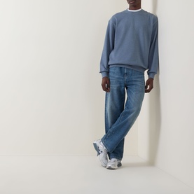 Model wearing Carhartt Caspian Sweatshirt in Shady Blue Heather, crew neck, dropped shoulders, styled with light-wash jeans and white trainers.