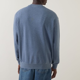 Model wearing Carhartt Caspian Sweatshirt in Shady Blue Heather, crew neck, ribbed trims, back view, styled with blue jeans.