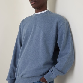 Model wearing Carhartt Caspian Sweatshirt in Shady Blue Heather, crew neck, dropped shoulders, ribbed trims, styled with white T-shirt underneath.
