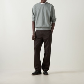 Model wearing Carhartt Caspian Sweatshirt in Shady Green Heather, crew neck, dropped shoulders, styled with dark brown trousers and black loafers.