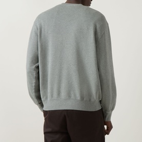 Model wearing Carhartt Caspian Sweatshirt in Shady Green Heather, crew neck, dropped shoulders, ribbed hem, back view, styled with dark trousers.
