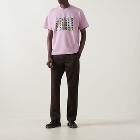 Model wearing Carhartt Coordinates Logo T-Shirt in Hortensia pink with graphic print, styled with dark brown trousers and black loafers.